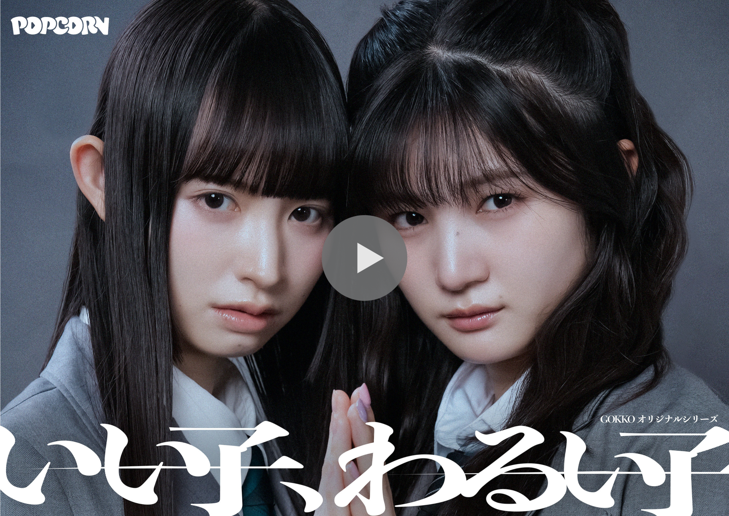Two young women with long dark hair closely framed on a poster, with a large play button overlay indicating a video thumbnail.
