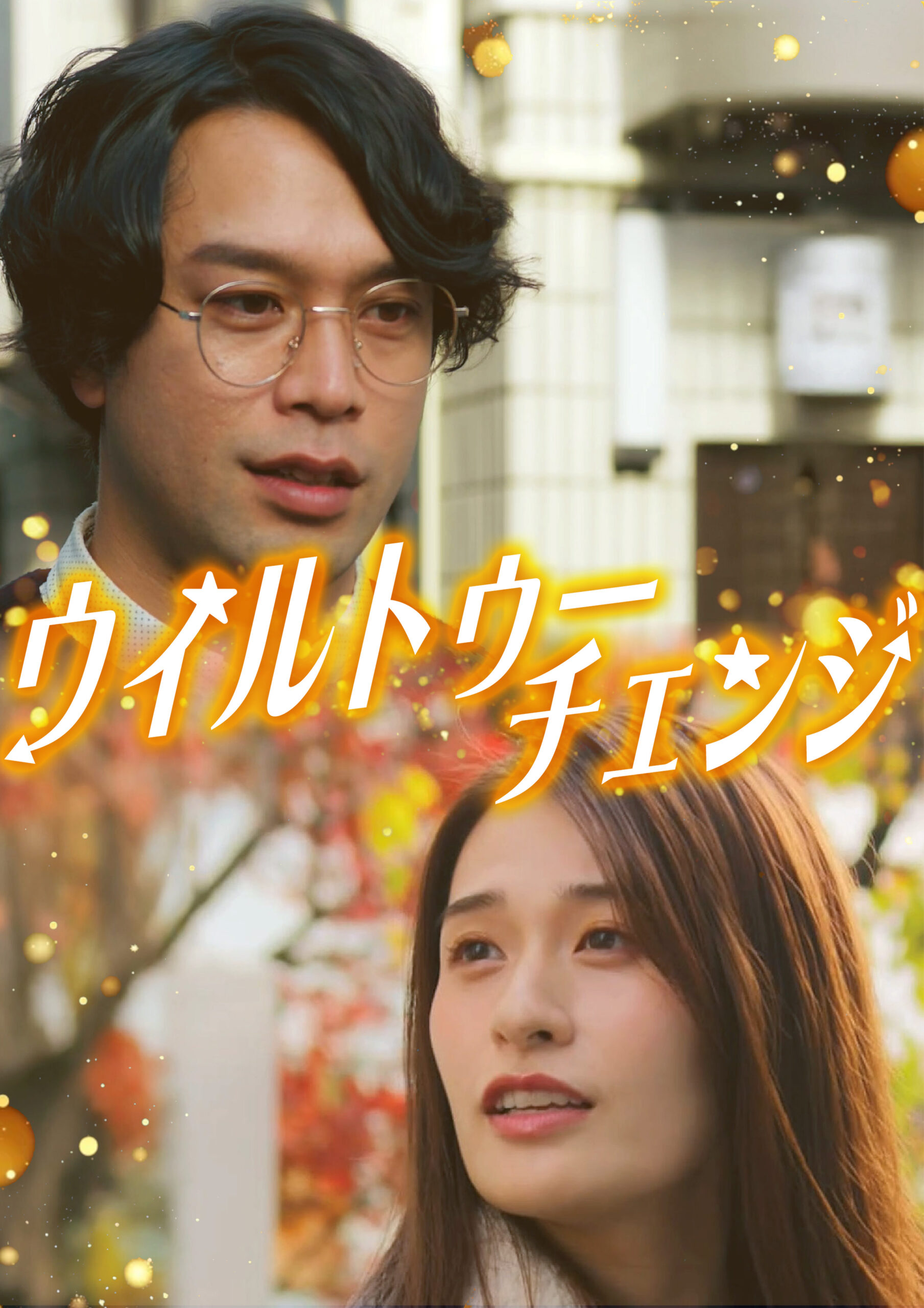 Two people, a man with glasses and a woman partially visible, outdoors with a blurred background and a bold orange Japanese text overlay plus gold confetti for a festive banner.